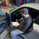 A man in a Boston Red Sox hat looks at a computer screen inside a 2001 Porsche 911.
